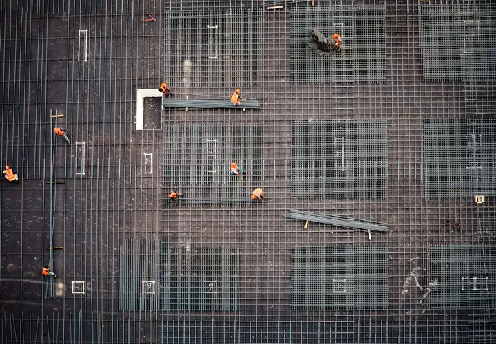 A crew placing rebar across a large slab, seen from straight above