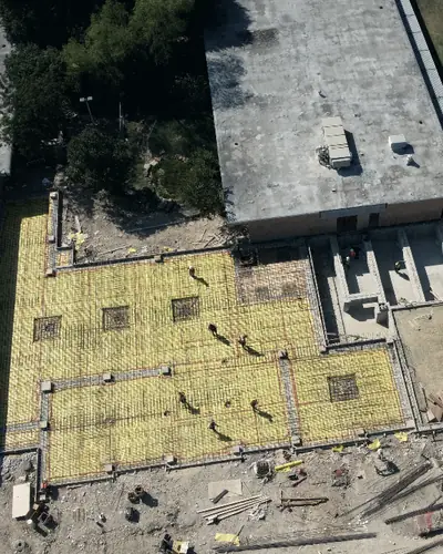 Rebar laid out for new slabs beside an existing building, seen from the air